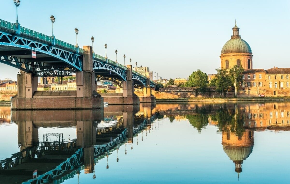 Image Toulouse Un pont sur la rivière avec une église en arrière-plan.